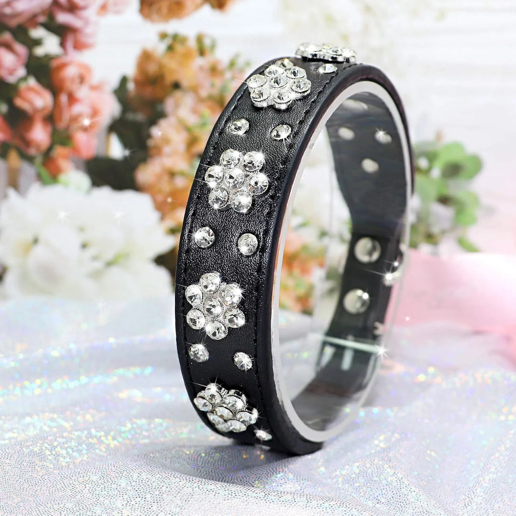 Close-up of a decorative black dog collar with sparkling rhinestone flowers and studs on PU leather.