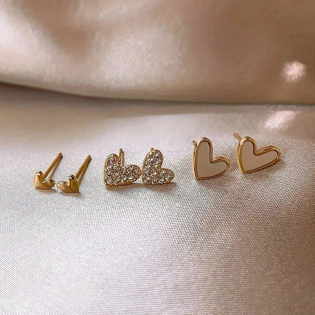 Three pairs of women's heart-shaped alloy earrings in electroplated colours on display