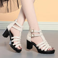 Women's beige summer high heel shoes with hollow-out design and rhinestone decoration on a buckle.