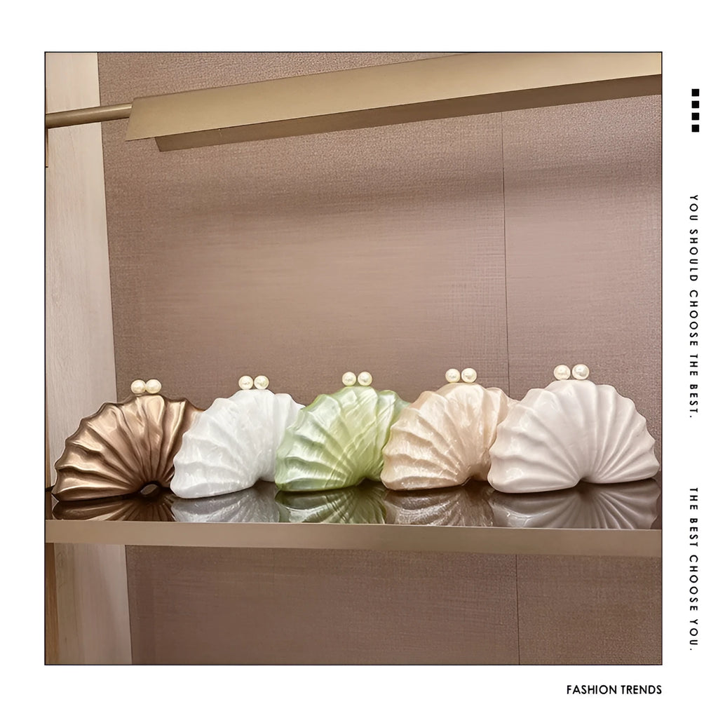 Acrylic shell-shaped clutch bag in champagne colour with chain detail on solid background