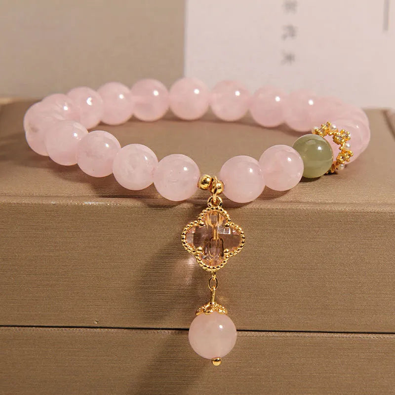 Pink crystal bracelet with four-leaf clover pendant and rhinestone details on women's wrist