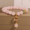 Pink crystal bracelet with four-leaf clover pendant and rhinestone details on women's wrist