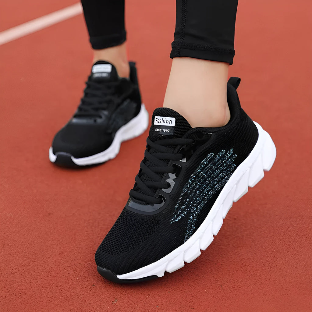 Flat running sneakers with cross-strap detail in black or white colours
