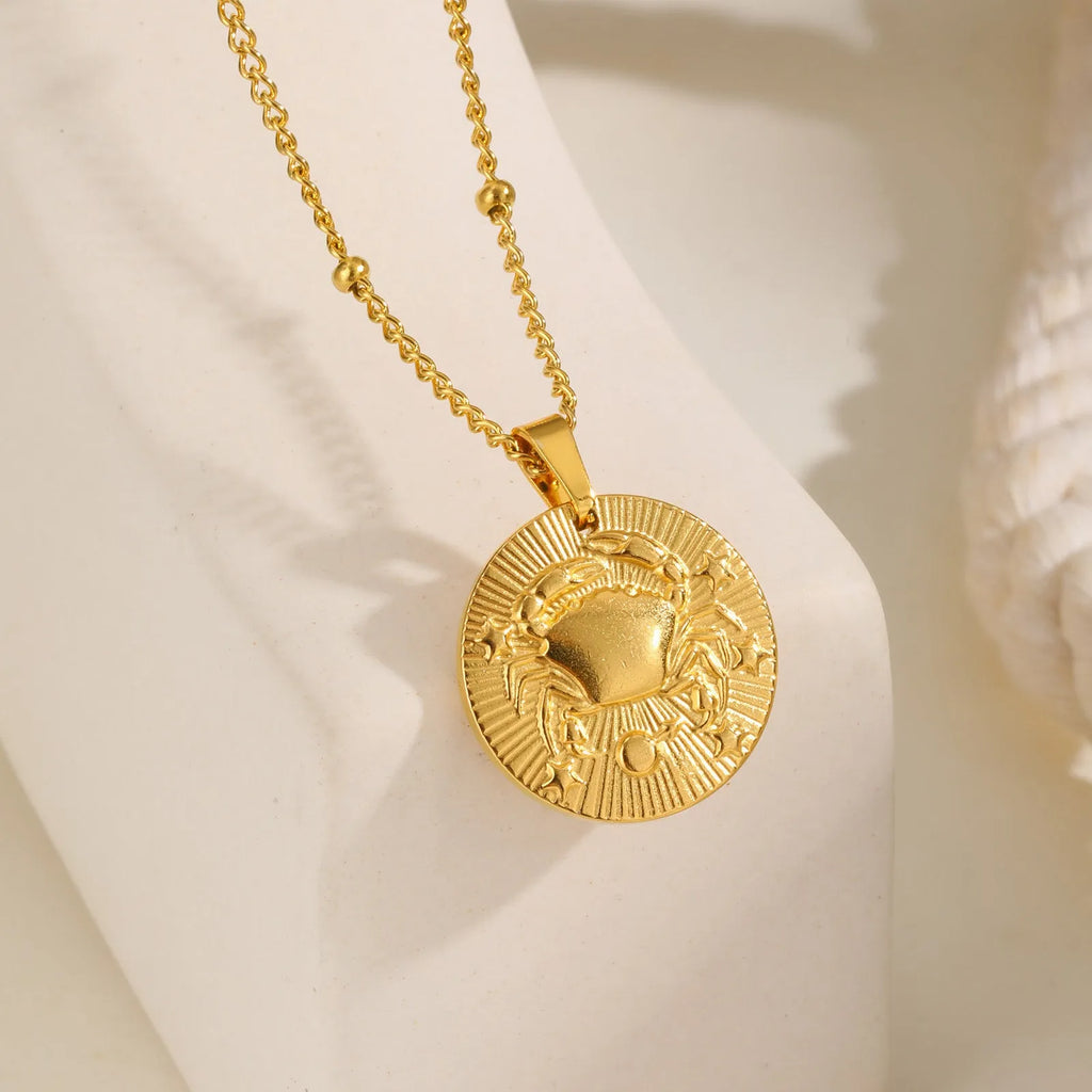 Stainless steel zodiac necklace with round pendant showing embossed constellation design on a cross chain.