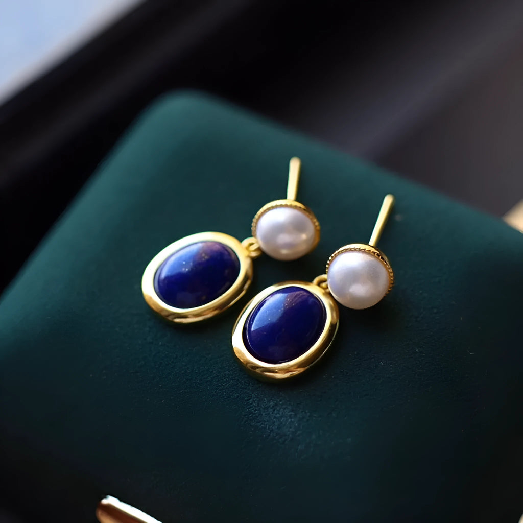 A pair of simple sterling silver stud earrings with a blue lapis lazuli pearl drop.