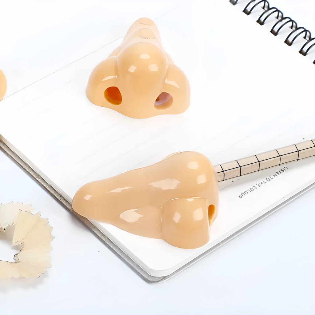 Flesh colour geometric plastic pencil sharpener with large nostril on a white background.