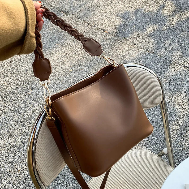 Khaki coloured PU leather one-shoulder crossbody bucket bag with woven detail on the front.