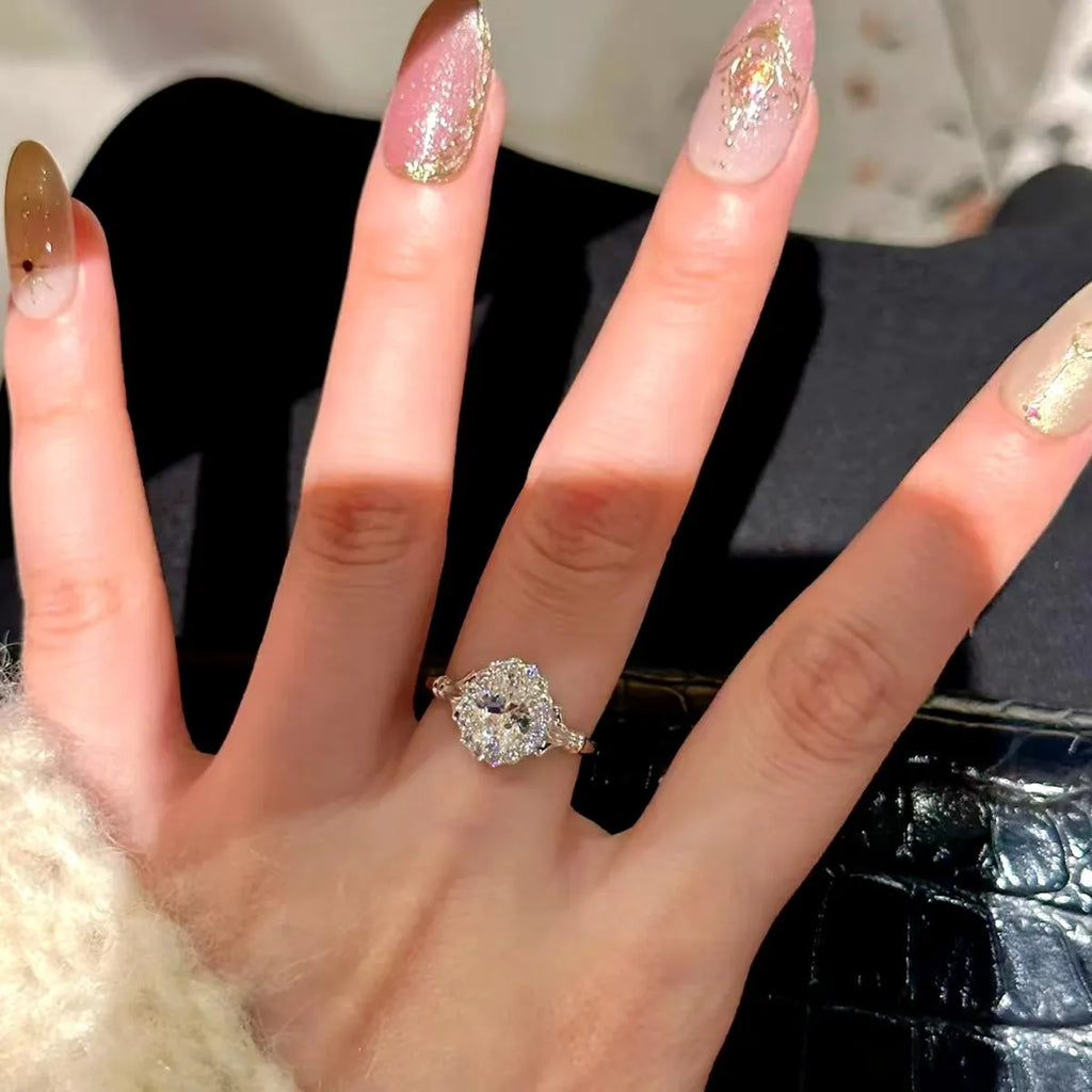 Silver geometric ring with a large diamond detail and adjustable opening on a woman's index finger.