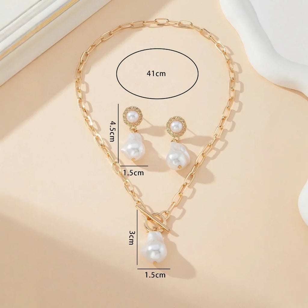 Gold-colour retro baroque pearl pendant necklace and matching ear studs set on a flat surface.