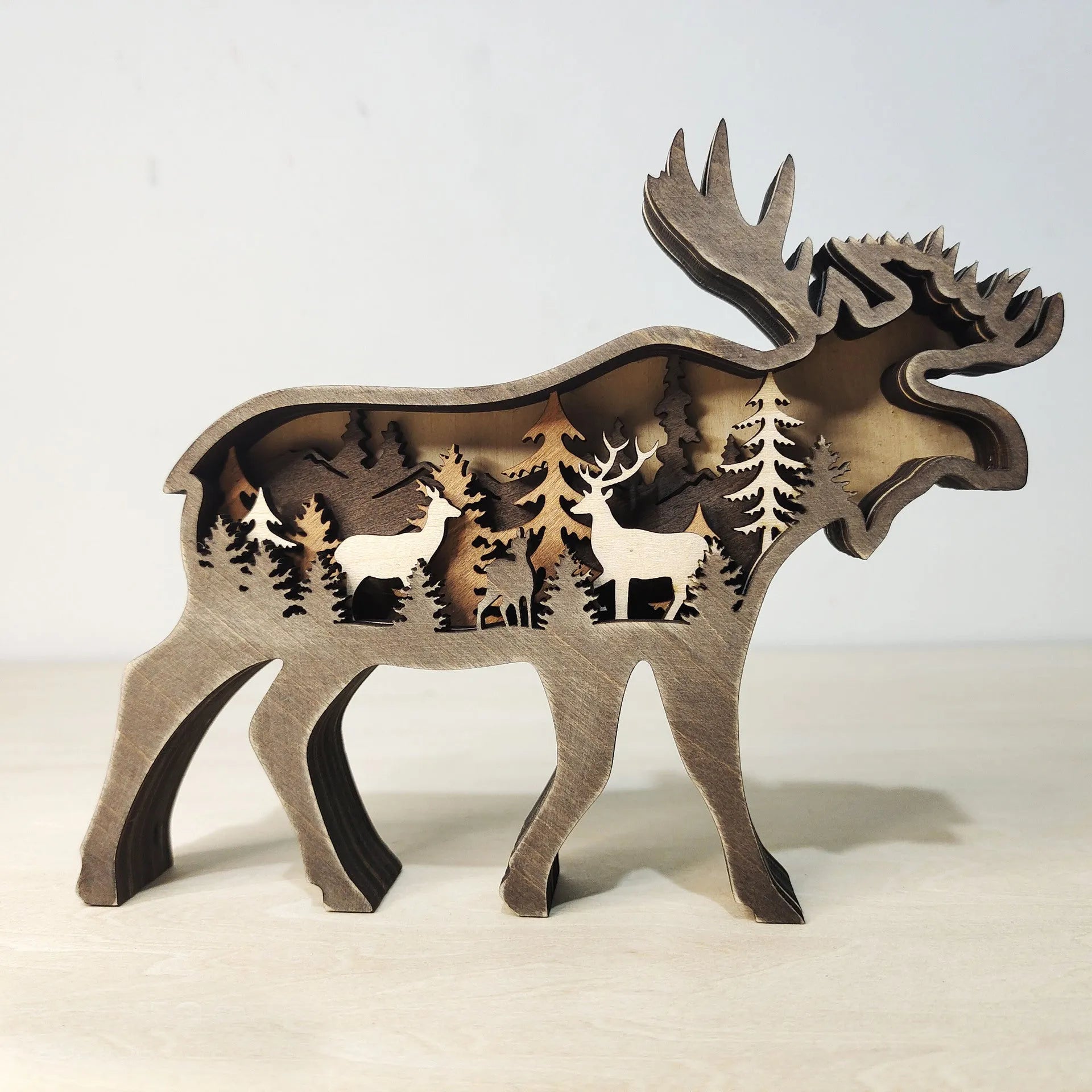 Two boxwood wooden ornaments, elk and brown bear, on a flat surface with natural wood finish