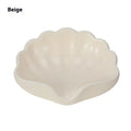 White shell-shaped plastic soap dish for bathroom counter next to sink.