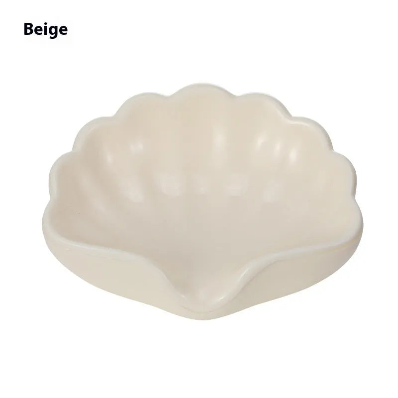 White shell-shaped plastic soap dish for bathroom counter next to sink.