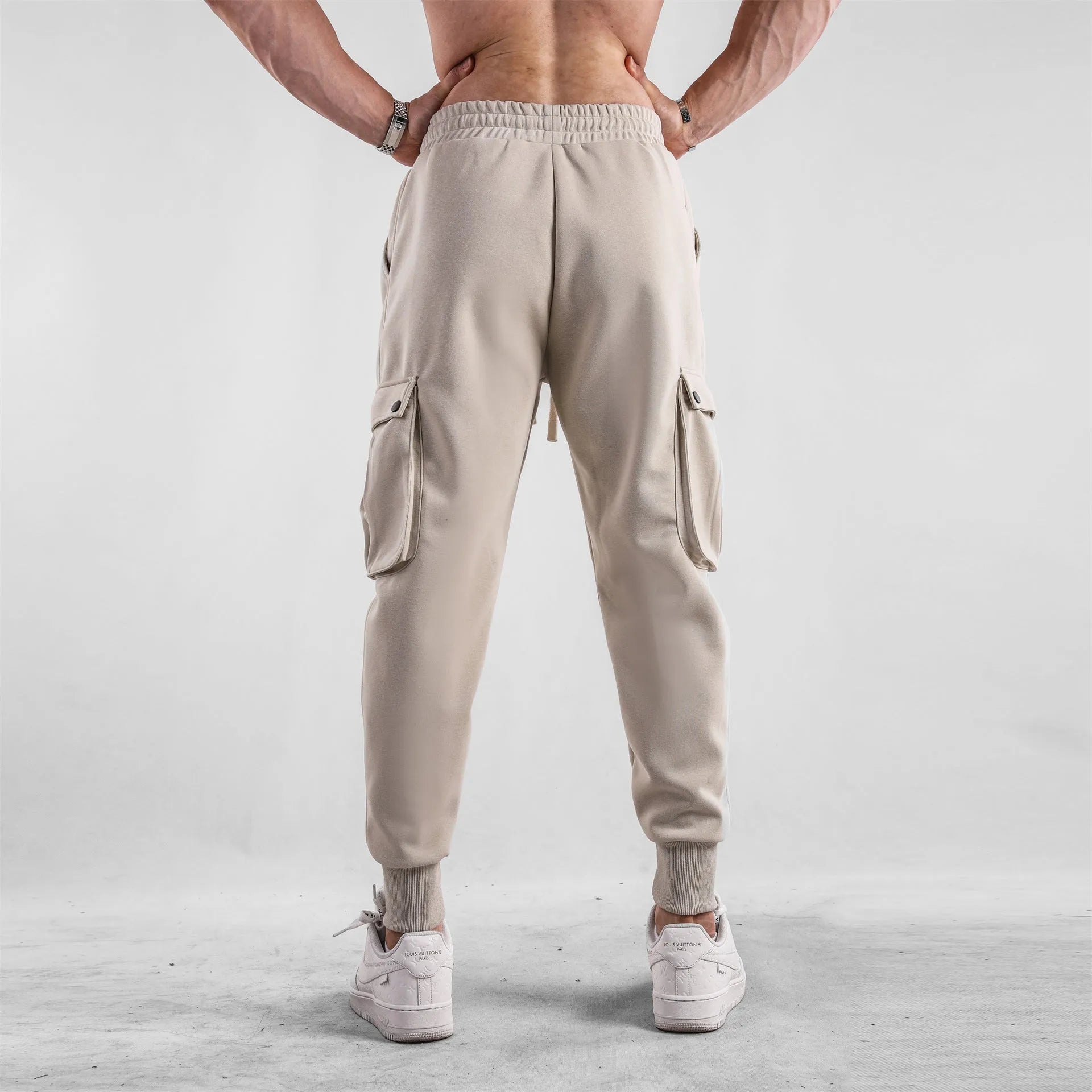 Man wearing loose light grey cotton trousers with ankle-tied cuffs and multiple pockets.