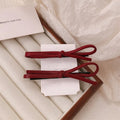 Wine red leather bow barrette hair clip shown on a model or background.