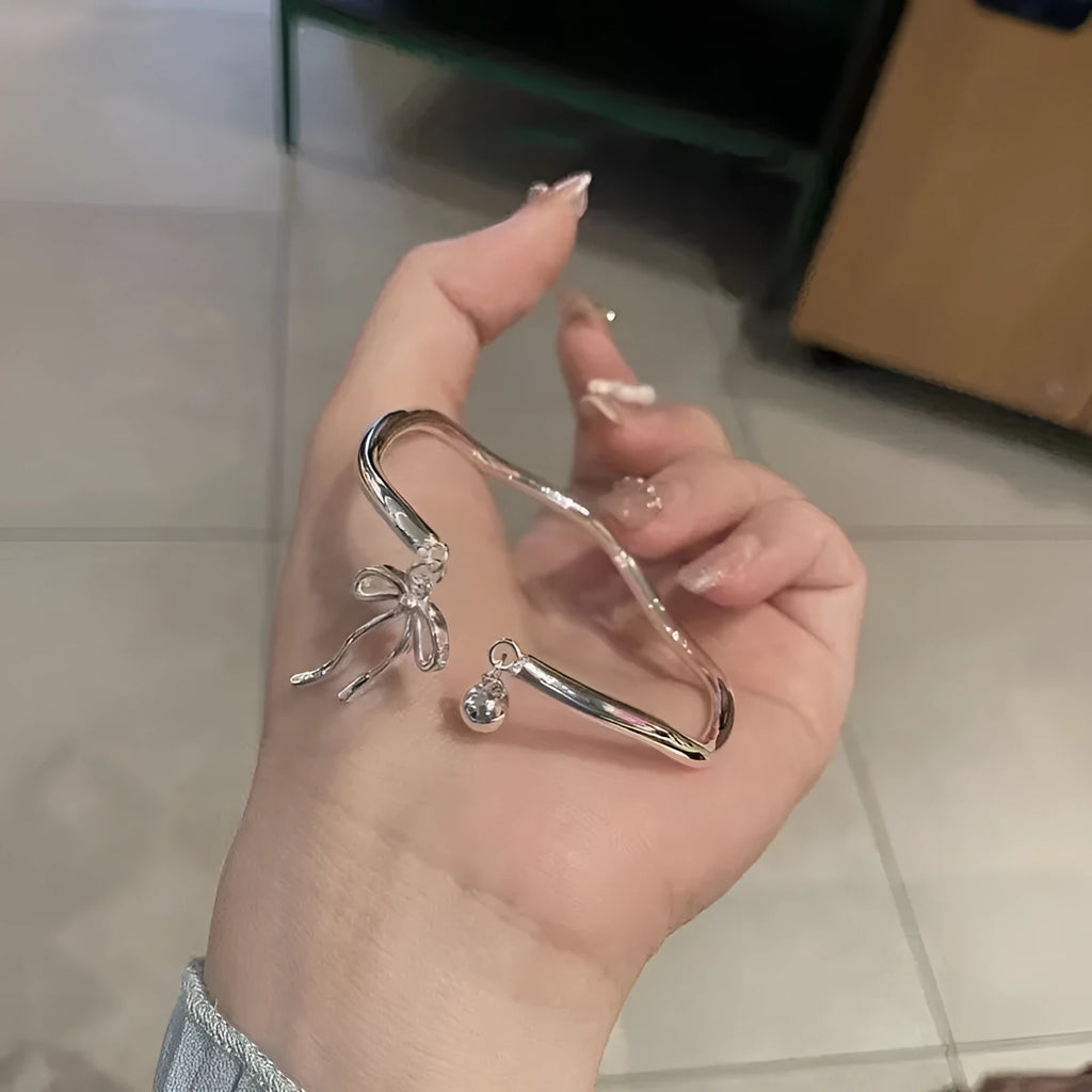 Silver adjustable bracelet with a detailed bow charm clasp on a white background.
