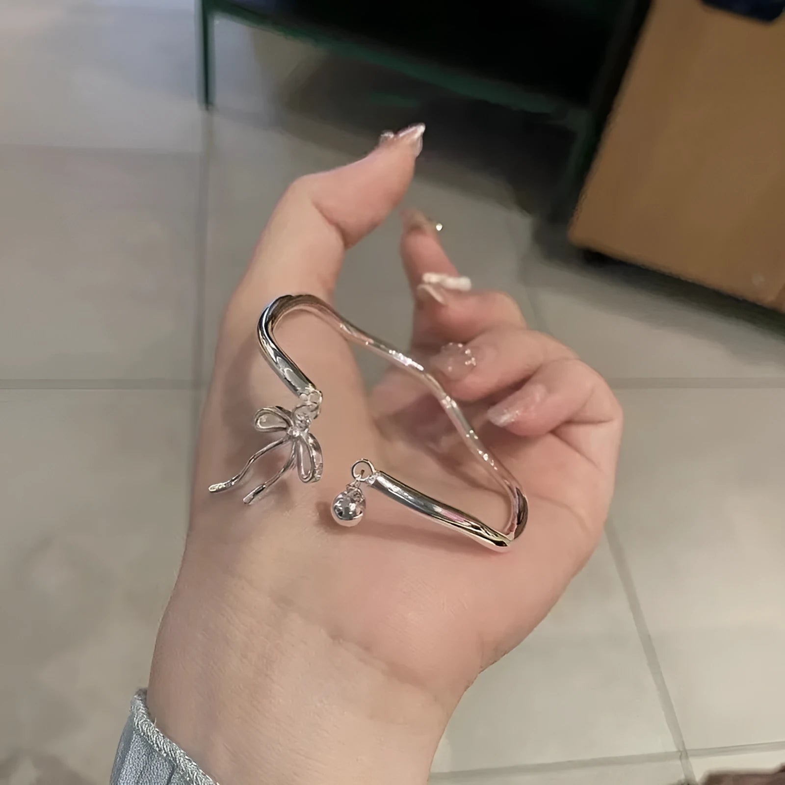 Silver adjustable bracelet with a detailed bow charm clasp on a white background.