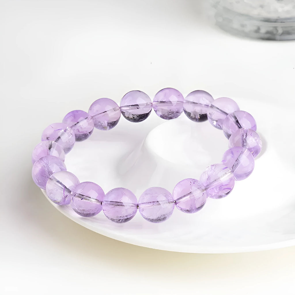 Lavender coloured amethyst crystal bracelet with round beads and a geometric water ripple design on a wrist.