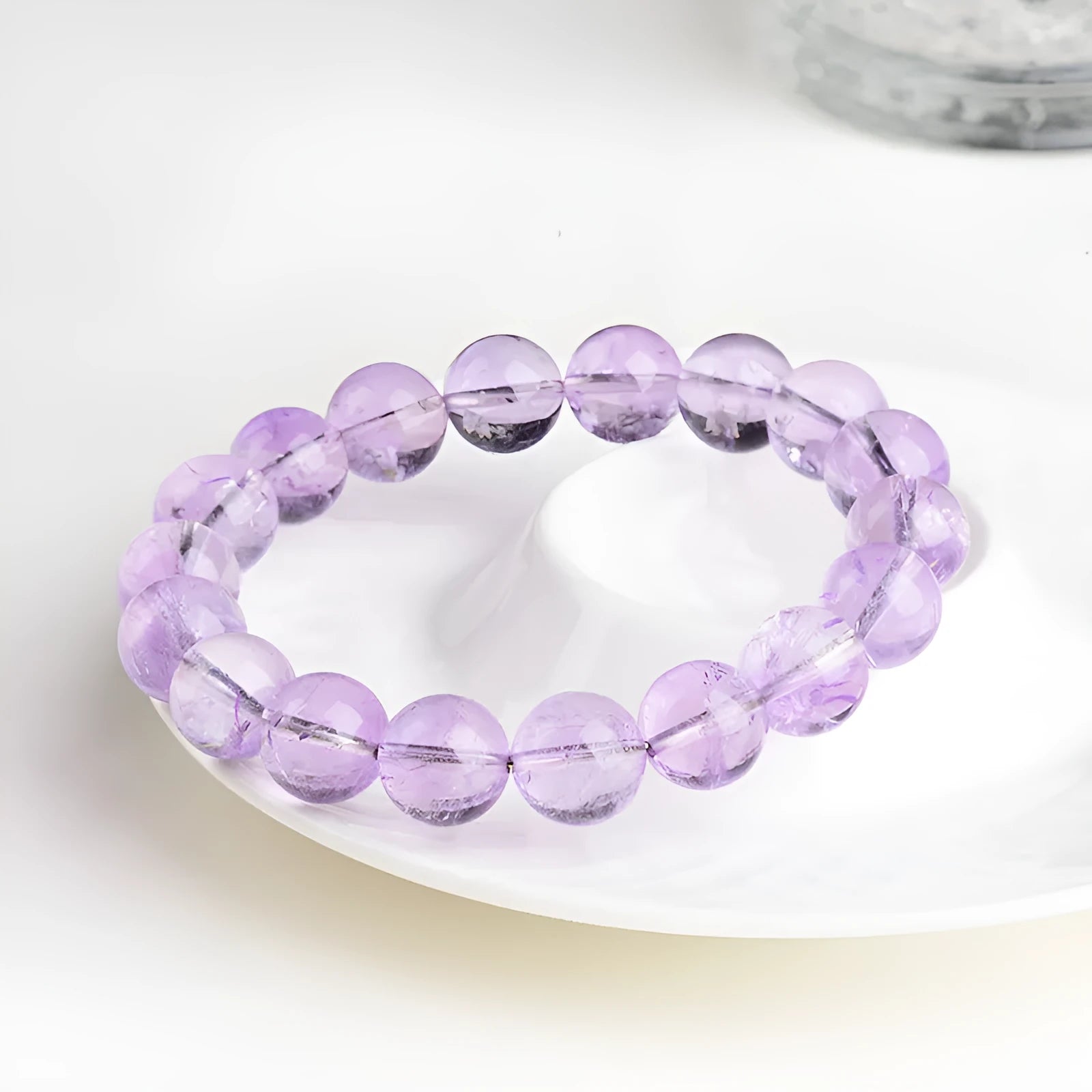 Lavender coloured amethyst crystal bracelet with round beads and a geometric water ripple design on a wrist.