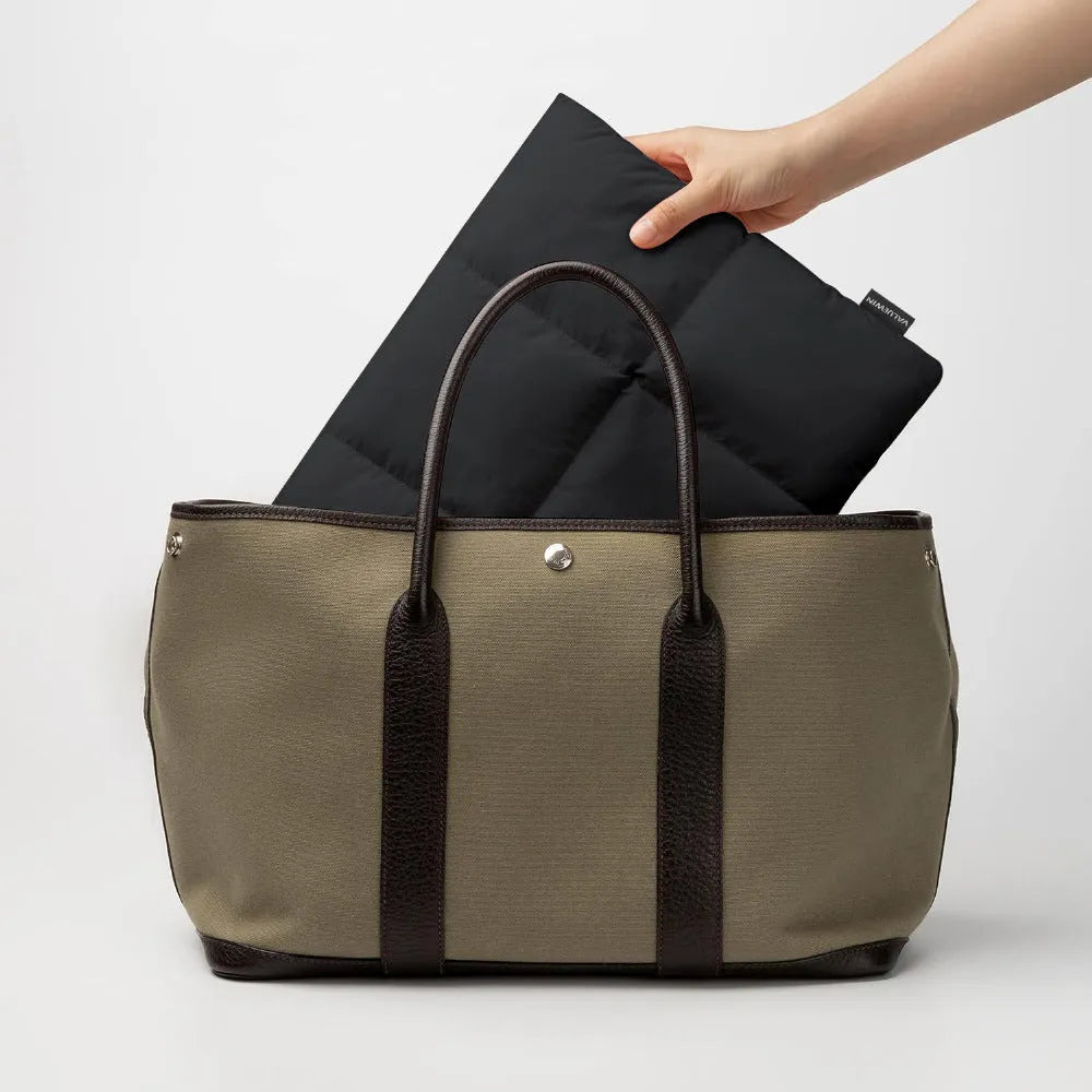 Soft fluffy polyester laptop sleeve in black with visible sewing thread detail, shown next to a laptop.