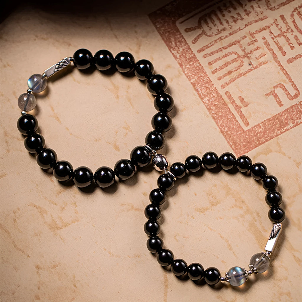 Black obsidian Buddha bead couple bracelets showing 8mm and 10mm sizes on a background.