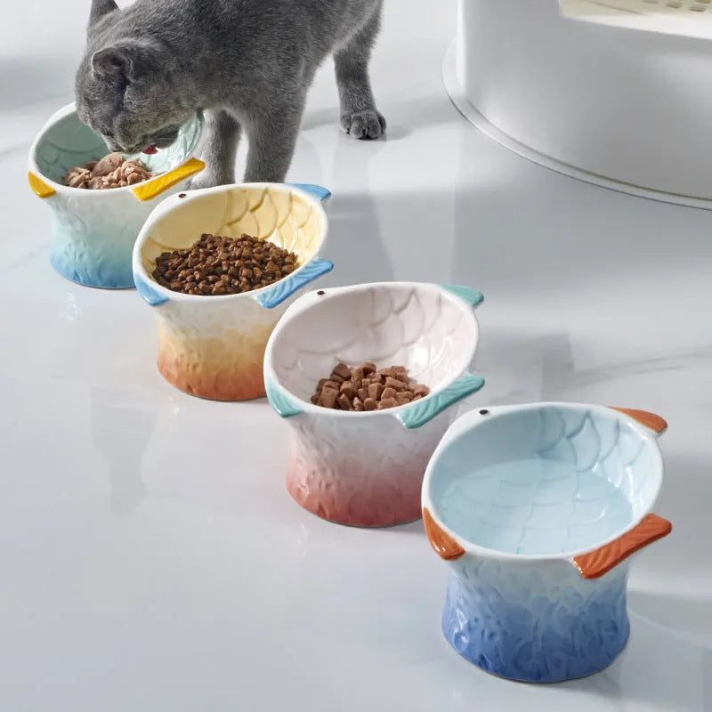 Set of four blue, fish-shaped ceramic cat bowls with a tilted design on a kitchen counter.