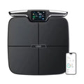 Black eight-electrode body fat scale on a floor, showing a simple square design with integrated electrodes.