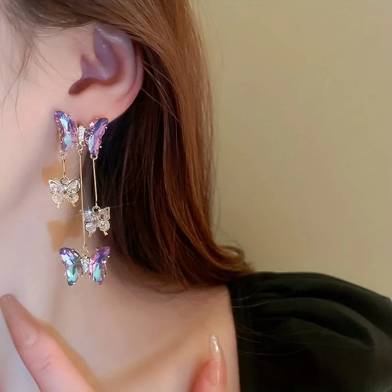 A pair of blue purple butterfly tassel drop earrings with crystal flowers and silver needle details on alloy.