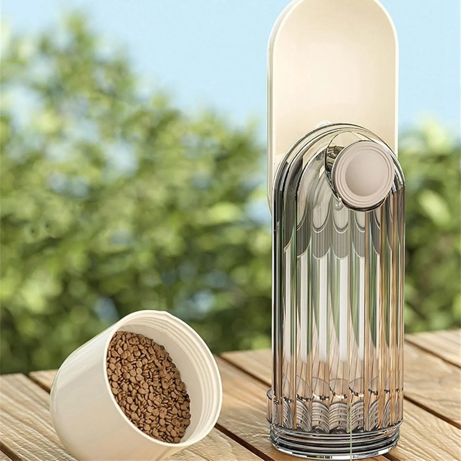Beige collapsible dog water bottle with food container at base, showing press dispenser and tray.