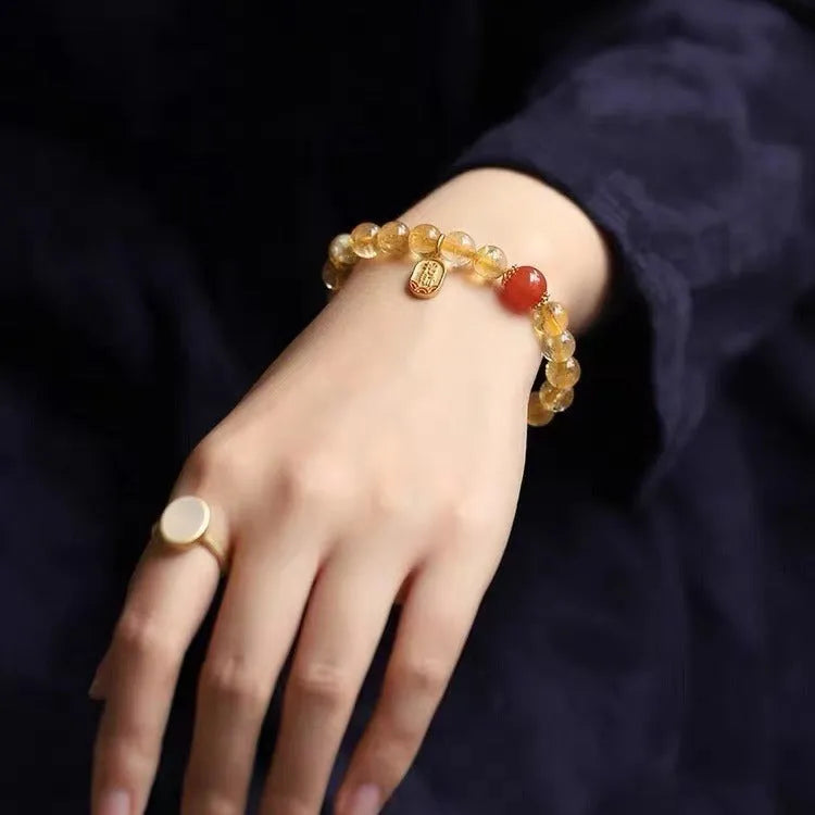 Natural red agate and gold ruby bead bracelet on a wrist, showing polished stones.
