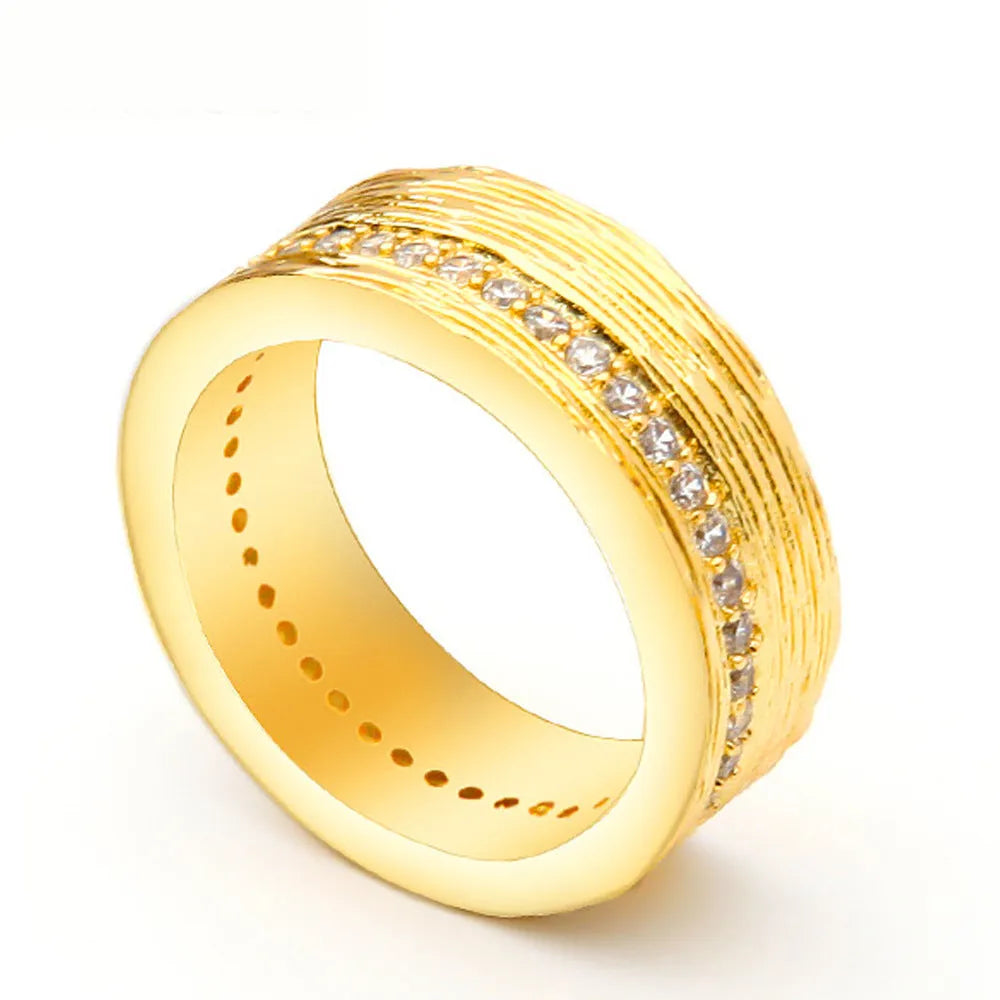Geometric gold-colour copper ring with zircon stone on a grey background.