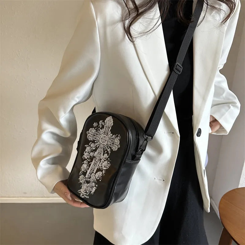 Black Halloween crossbody bag with cartoon pumpkin, ghost, and bat print, showing front and strap.