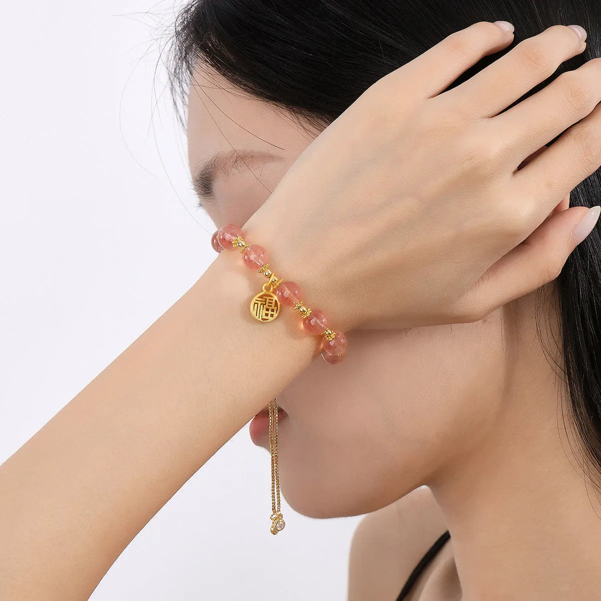 A geometric crystal bracelet in strawberry quartz colour with a fu character detail.