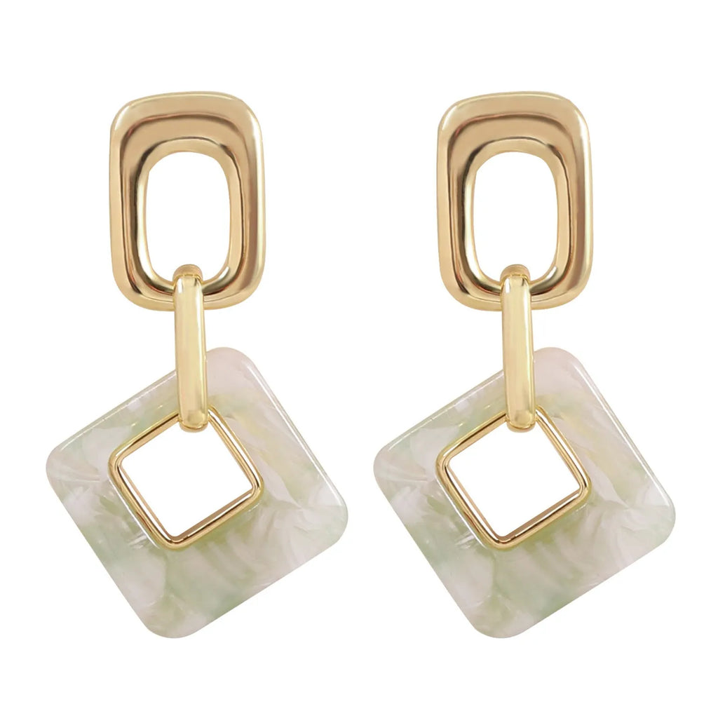 A pair of hollow square geometric earrings with a chamfered edge pattern in a gold tone finish.