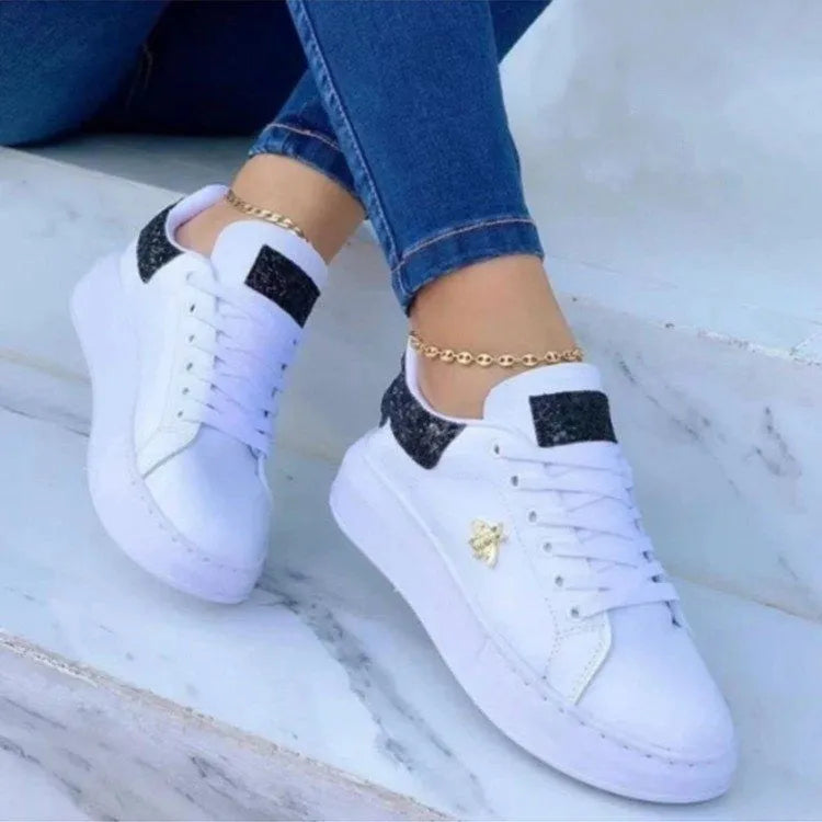 White low-top platform sneakers with lace-up closure and rubber sole on a light background