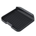 Large black cat litter pedal with slanted mouth and textured grooves beside a litter tray
