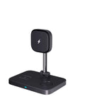 Black magnetic three-in-one wireless charger and cooling bracket on a desk, with phone upright and watch on base.