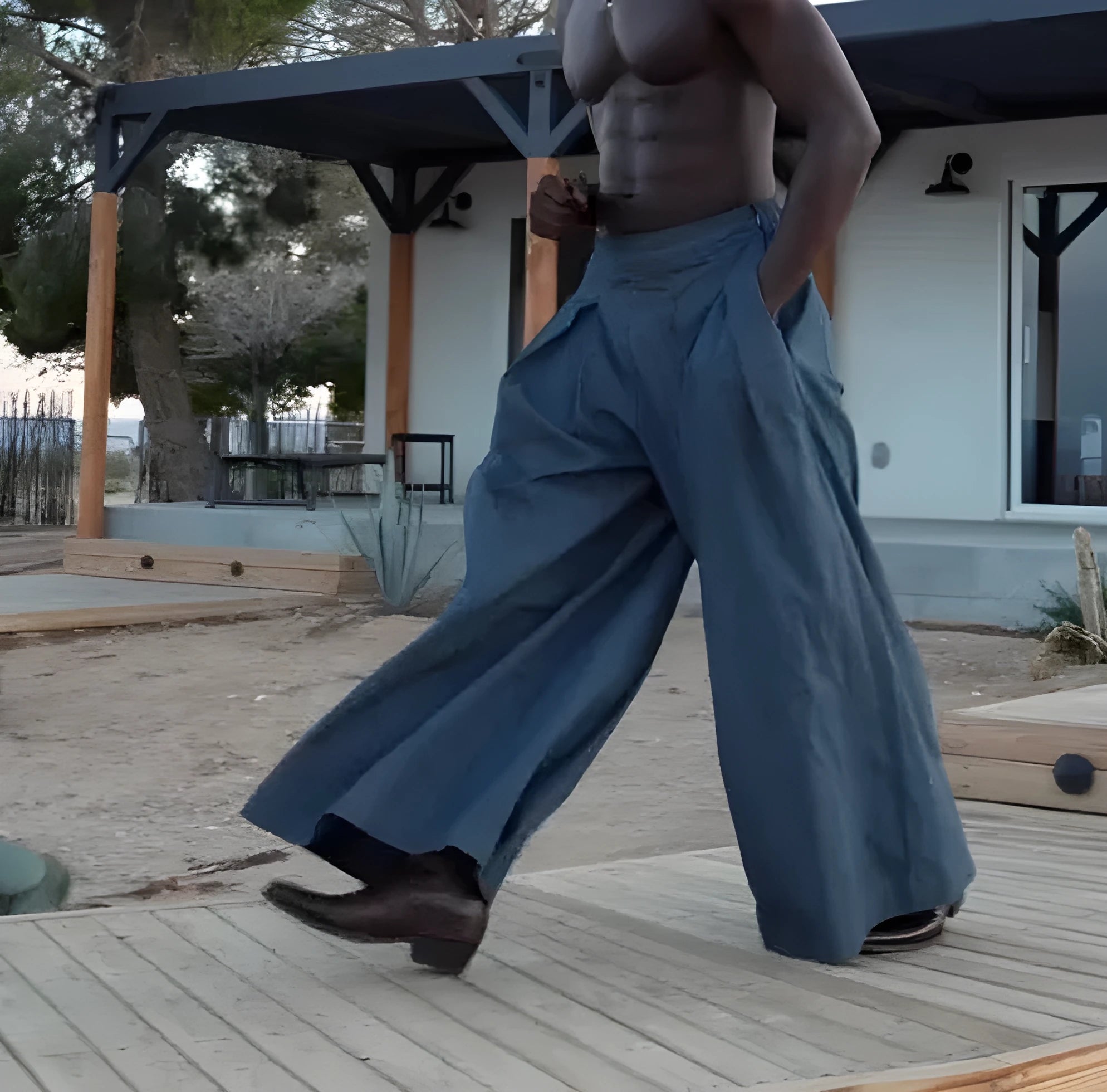 Men's grey pleated wide-leg trousers with an elasticated waistband on a hanger.