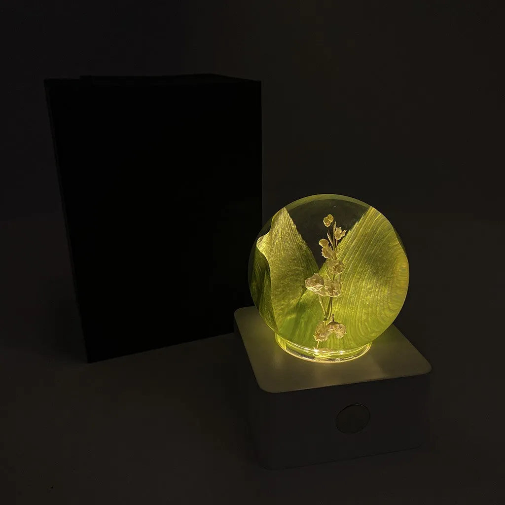 Small 8cm clear night light with a preserved dandelion and sunflower inside, lit with a warm glow.