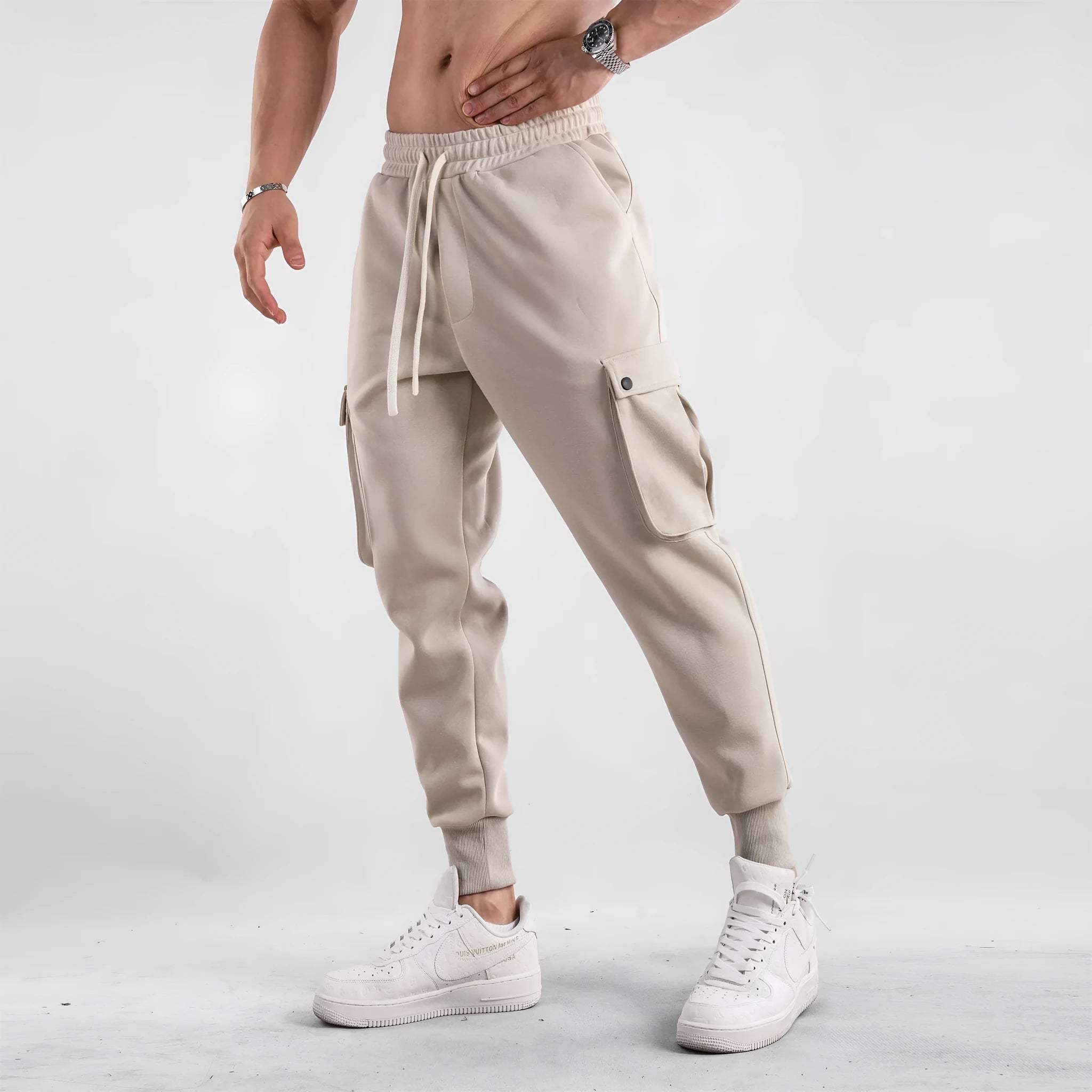 Man wearing loose light grey cotton trousers with ankle-tied cuffs and multiple pockets.