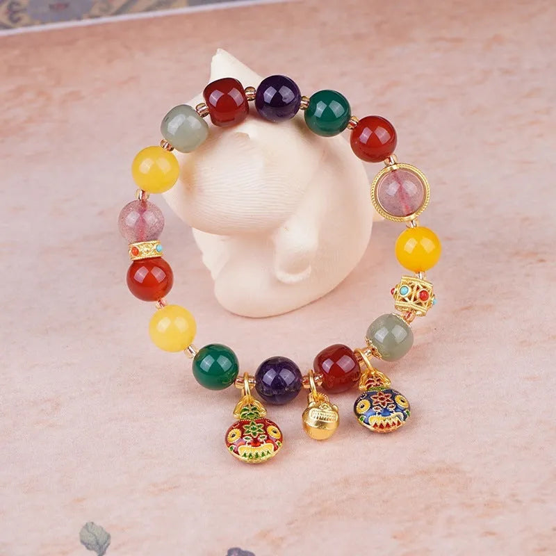 Close-up of a bracelet with a hand-woven gold beast charm and large brown agate beads.