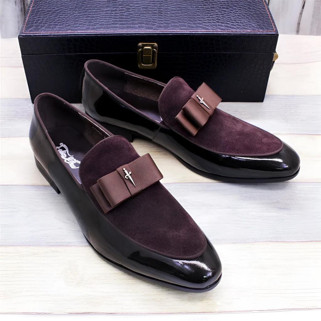 Men's black patent leather shoes with a gold tassel detail on a rubber sole.