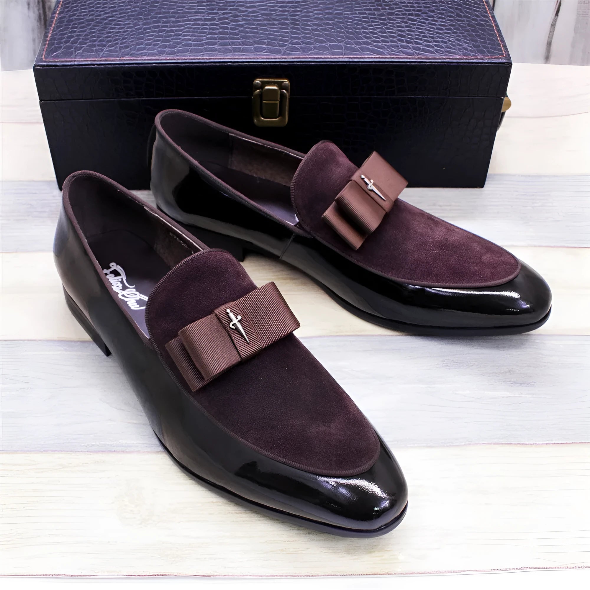 Men's black patent leather shoes with a gold tassel detail on a rubber sole.