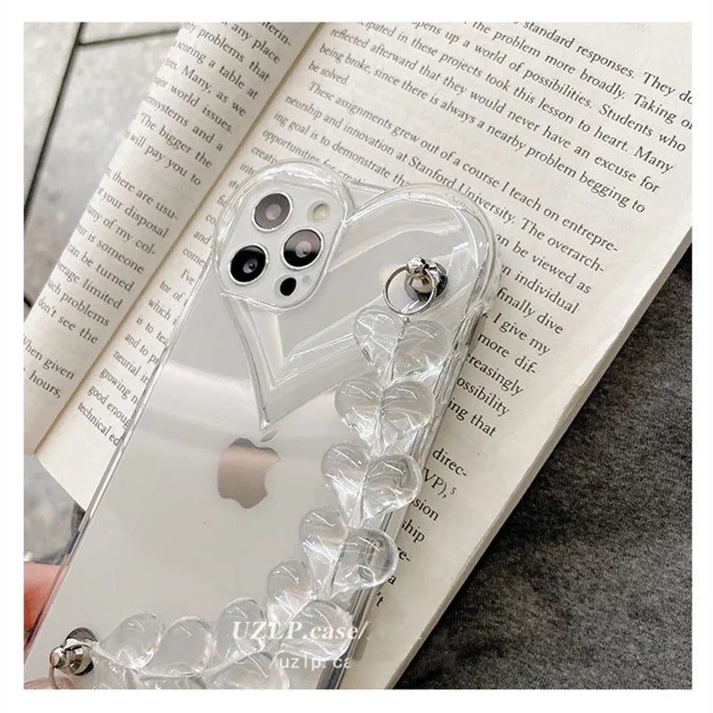Transparent iPhone case with an attached clear love heart charm bracelet on a TPU shell.
