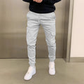 Man wearing loose-fit light blue polyester casual trousers with dimensional patch pockets and an elastic waistband.