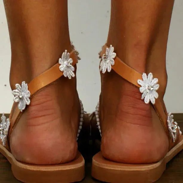 Brown women's flat Roman-style sandals with floral design on the artificial PU upper.