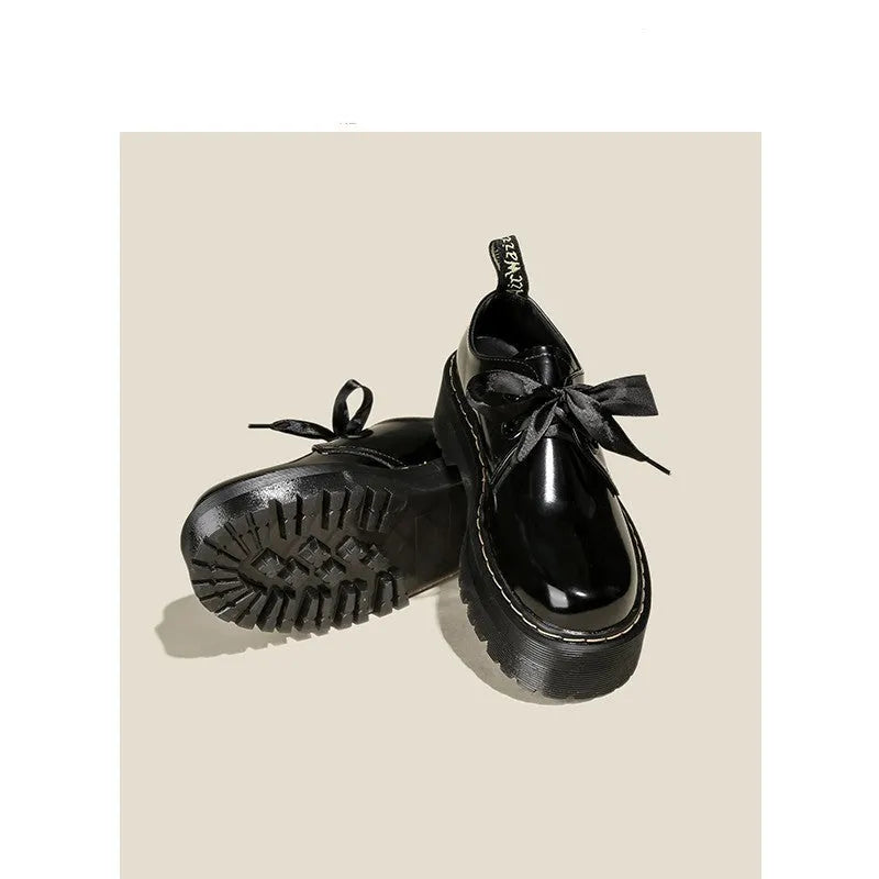 Women's black leather flat shoes with thick soles, cross straps, ribbons, and laced closure.