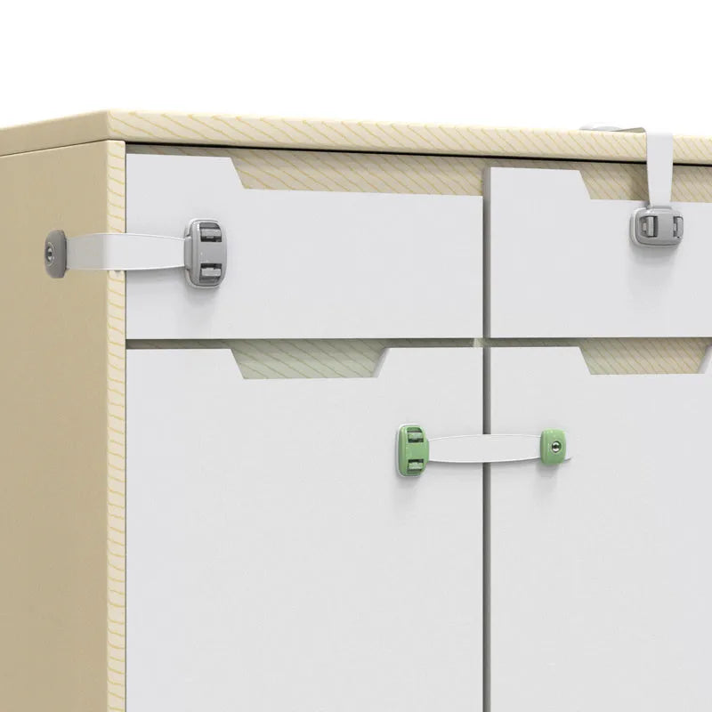 Grey and green adjustable child safety cabinet locks with adhesive backing on a kitchen drawer.