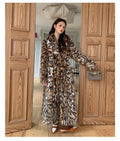 A woman's long faux fur coat with a fur collar and pockets, shown in a street fashion style.