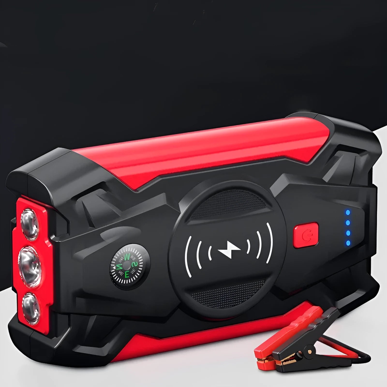 Red car emergency jump starter power pack with battery clamps and cables on a black storage box.