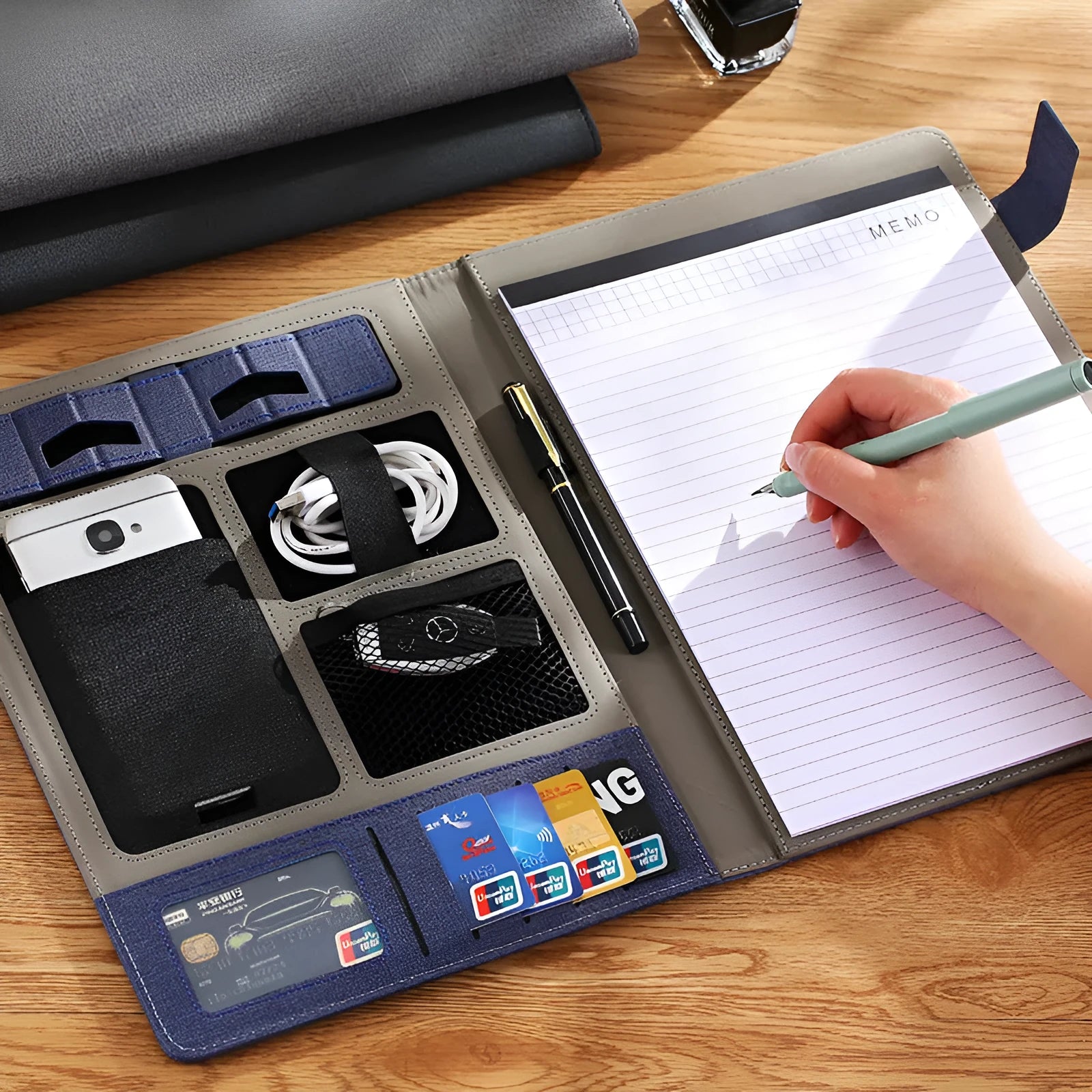 Black leather A4 business folder holding documents, with a pen and notepad visible.